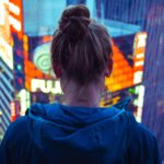 Woman in the city looking down on neon lights