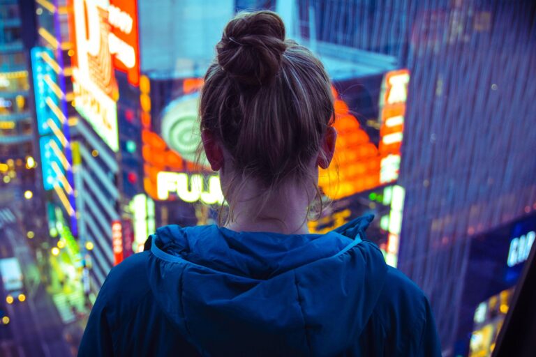 Woman in the city looking down on neon lights